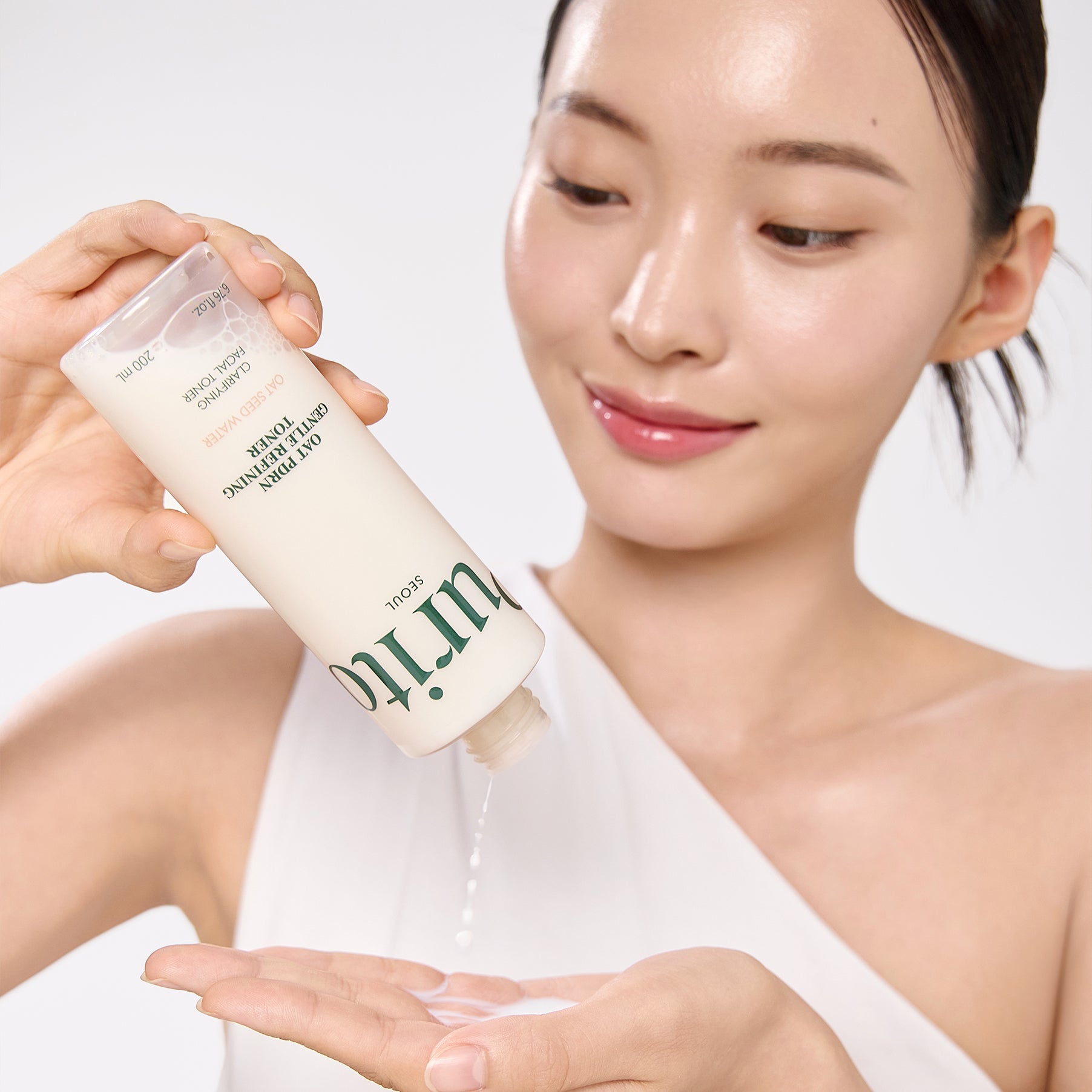 PURITO Oat PDRN Gentle Refining Toner 200ml de PURITO, femme applique le toner sur peau, gouttes sur fond blanc