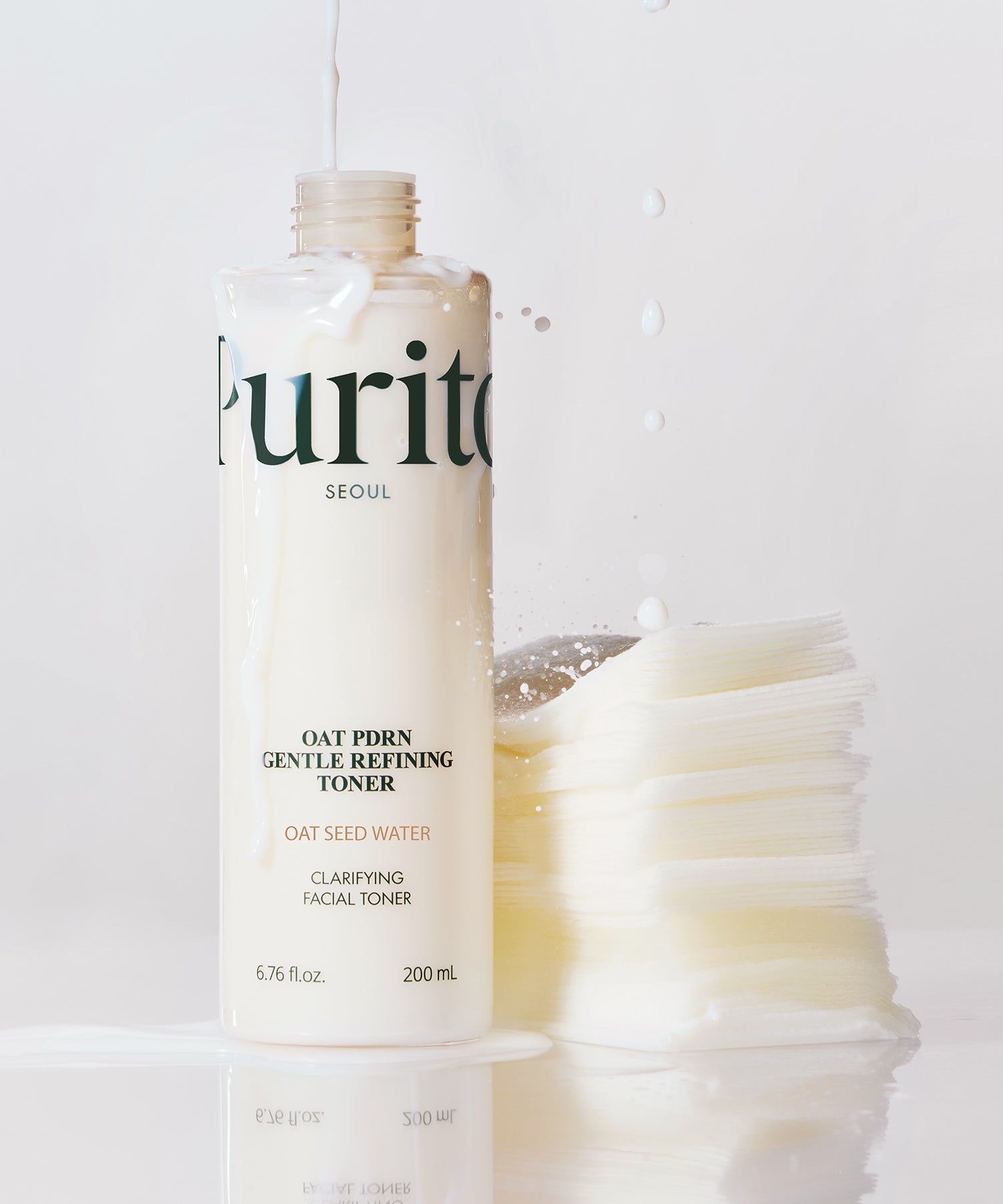 PURITO Oat PDRN Gentle Refining Toner 200ml, flacon crème sur fond blanc avec éclaboussures, branding Purito.