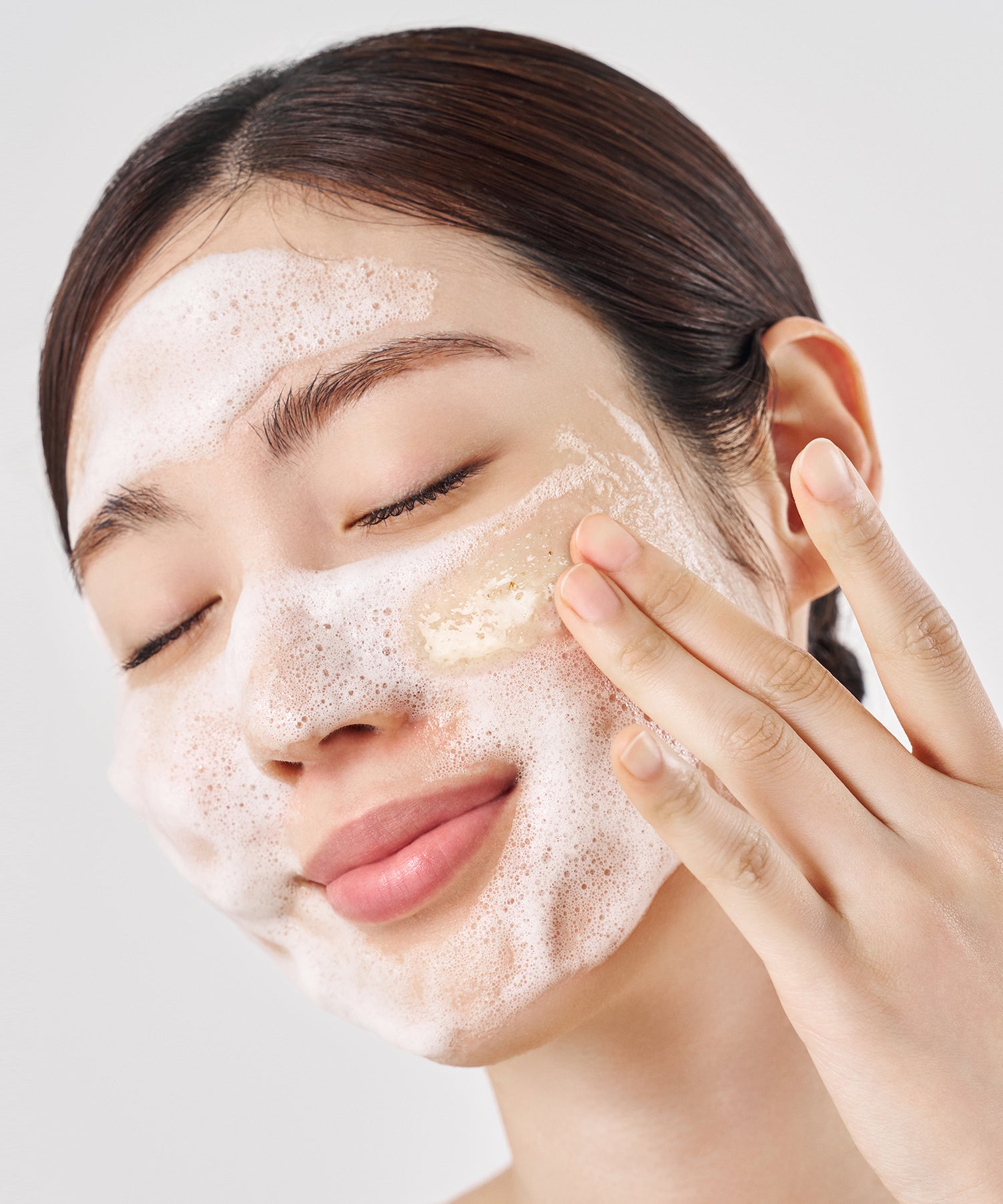 PURITO Oat in Gentle Exfoliating Face Cleanser, femme appliquant une mousse exfoliante à l’avoine, brand PURITO sur fond clair