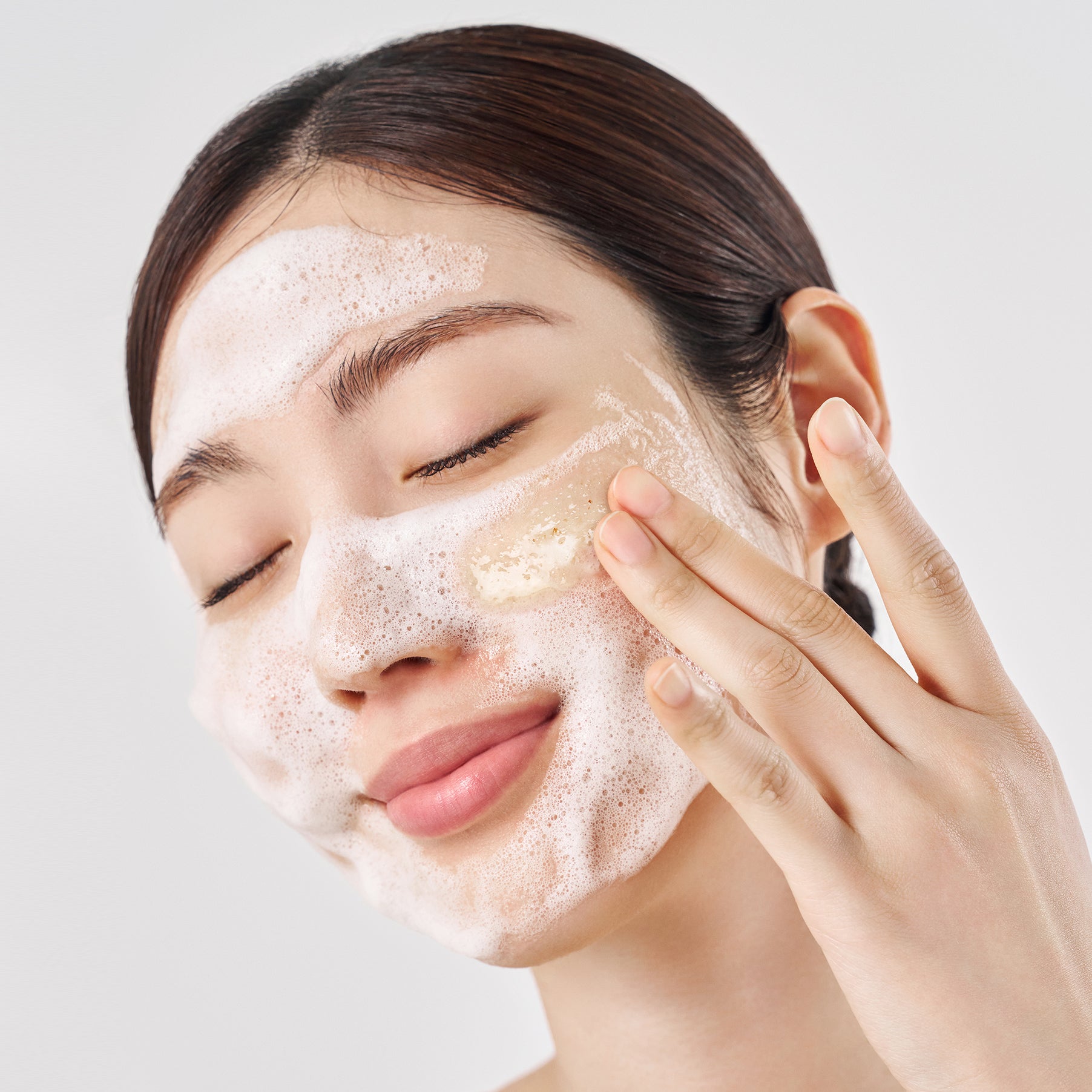PURITO Oat in Gentle Exfoliating Face Cleanser, femme appliquant une mousse exfoliante à l’avoine, brand PURITO sur fond clair
