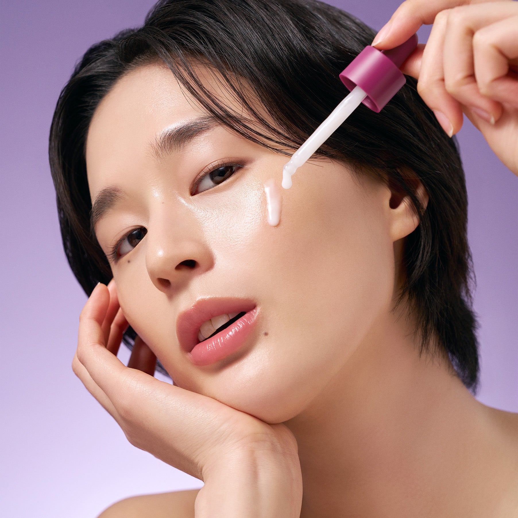 PURITO Timeless Bloom Bakuchiol Serum 30ml de Purito : une femme applique le sérum au compte-gouttes sur le visage, fond violet.