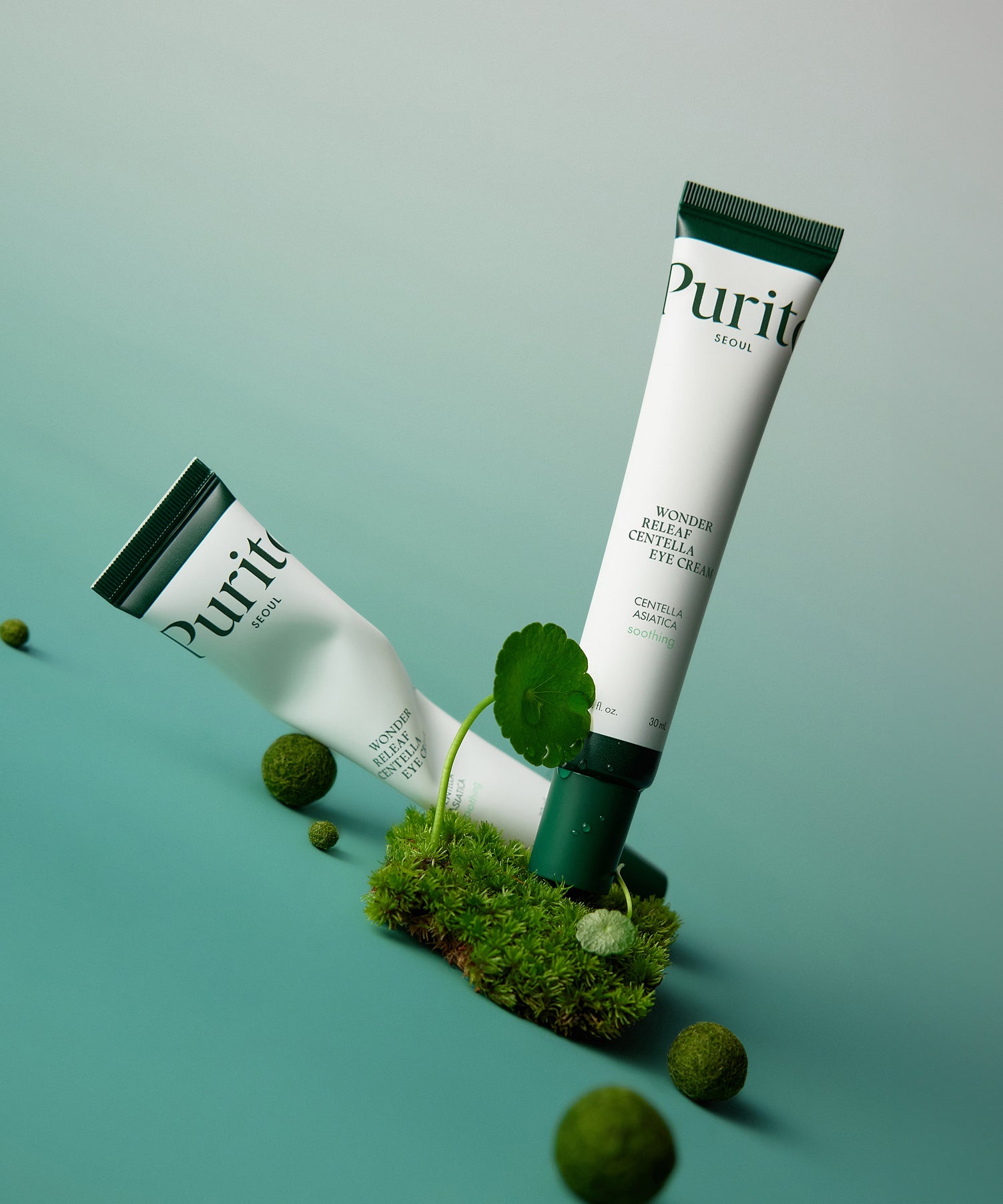 PURITO Wonder Releaf Centella Eye Cream de Purito sur fond vert, tube et boîte avec feuilles de centella et mousse.