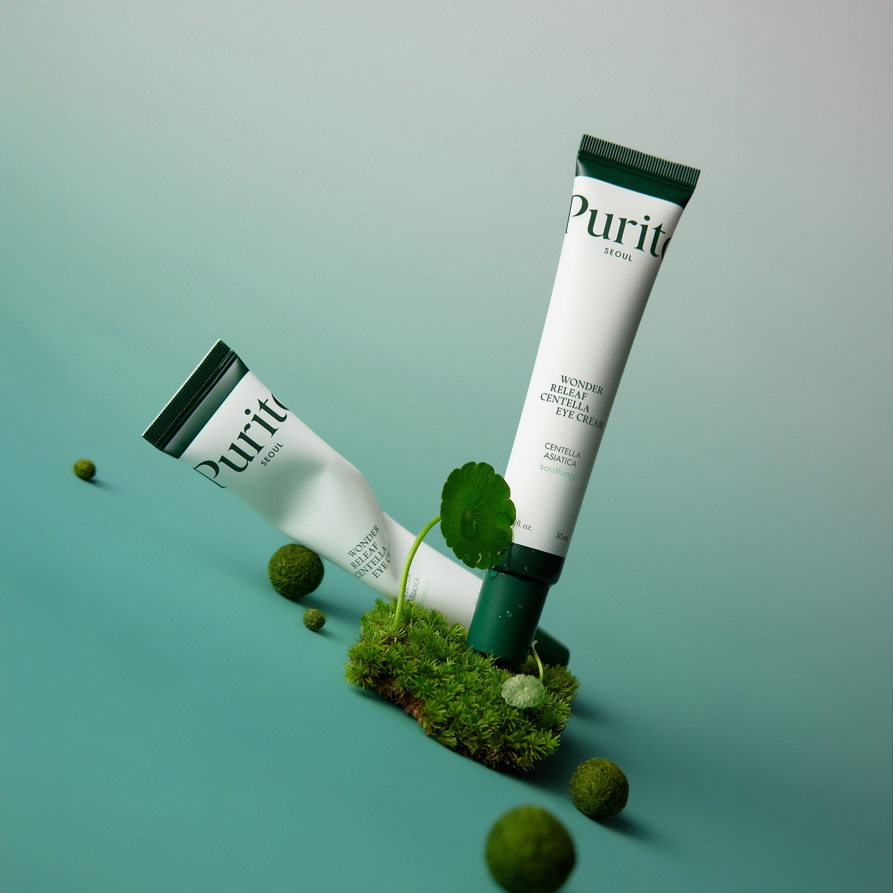 PURITO Wonder Releaf Centella Eye Cream de Purito sur fond vert, tube et boîte avec feuilles de centella et mousse.