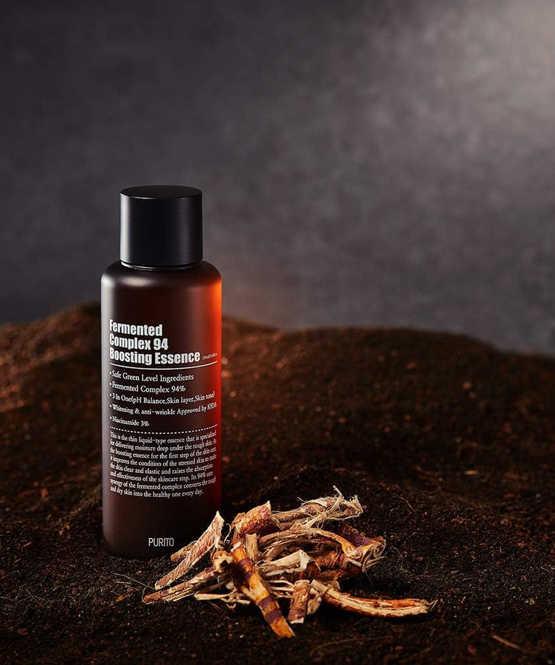 PURITO Fermentedd Complex 94 Boosting Essence 150ml sur un fond terreux avec des ingrédients naturels, mise à en valeur du produit.