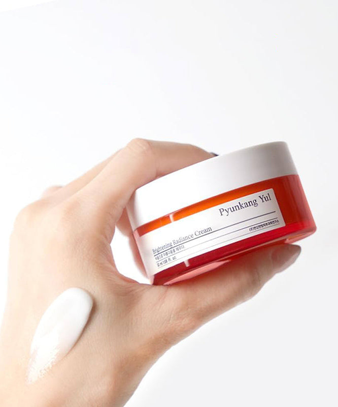 Crème de radiance PYUNKANG YUL Brightening Radiance Cream 50ml en pot rouge, texture légère et hydratante, tenue à la main, 50ml.