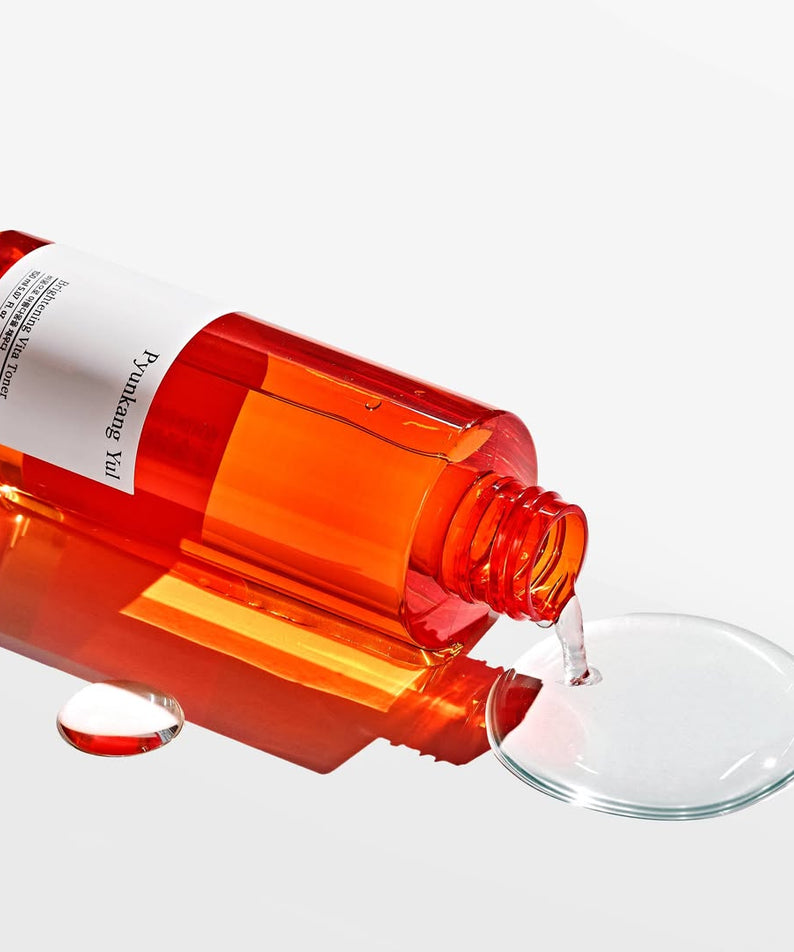 Flacon de PYUNKANG YUL Brightening Vita Toner 150ml renversé avec liquide transparent coulé, tonique éclat pour tous types de peau.