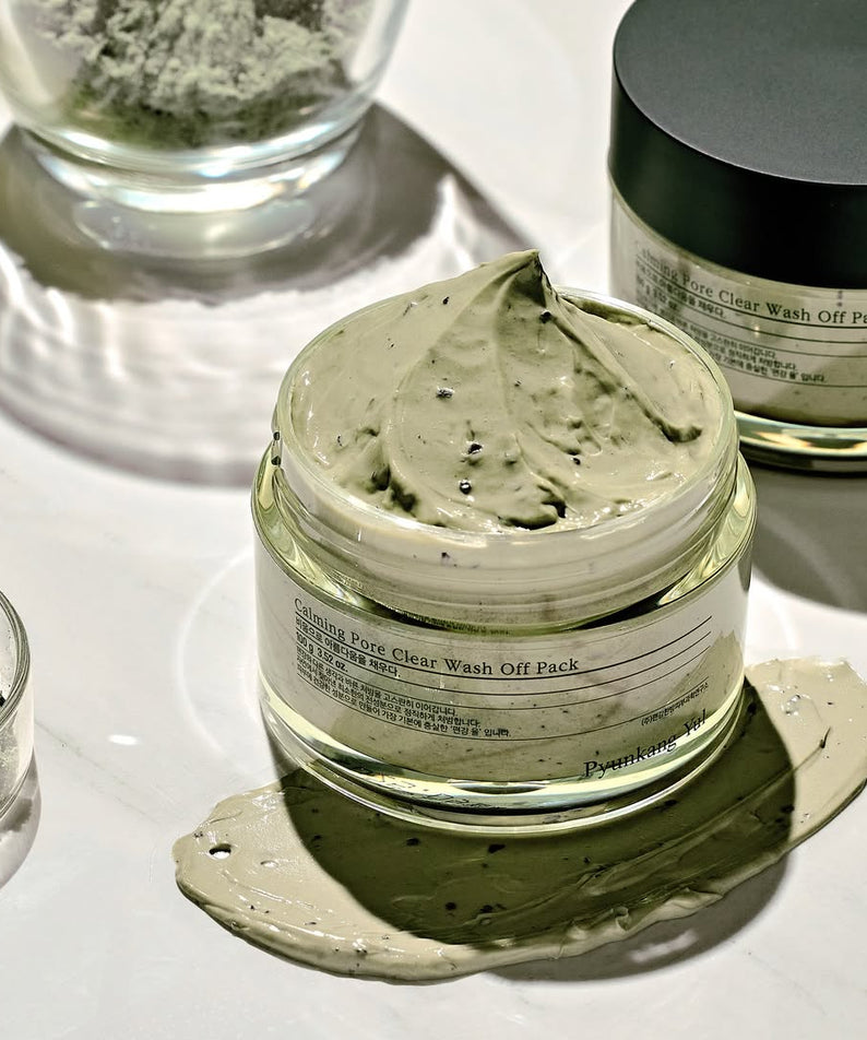 PYUNKANG YUL Calming Pore Clear Wash Off Pack 100ml sur une table blanche, pot ouvert, masque vert visible, soin visage nettoyant.