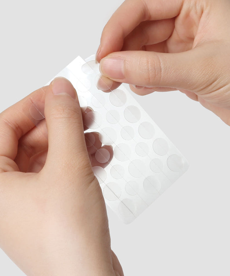 Feuille de patchs pour acné PYUNKANG YUL True Clear Spot Patch Intensive Care Vibevel 165 pcs en usage, gros plan, mains féminines.