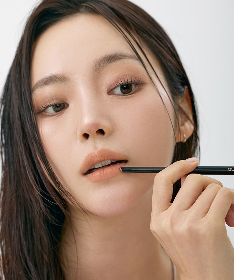QUA-T NEW My Mood Lip Liner : femme maquille ses lèvres avec un crayon, fond studio lumineux, marque QUA-T.