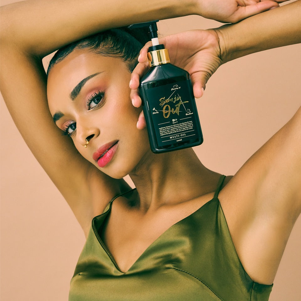 QUA-T Samjin Out Oil 220ml Samjin, flacon vert tenu par des mains sur une femme en pose spa, fond beige.