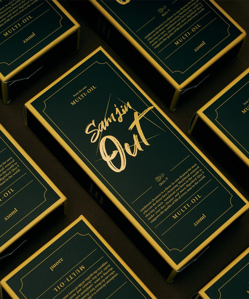 QUA-T Samjin Out Oil 220ml Samjin Out, flacons vert or en série sur fond sombre, étiquette “Multi-Oil”.