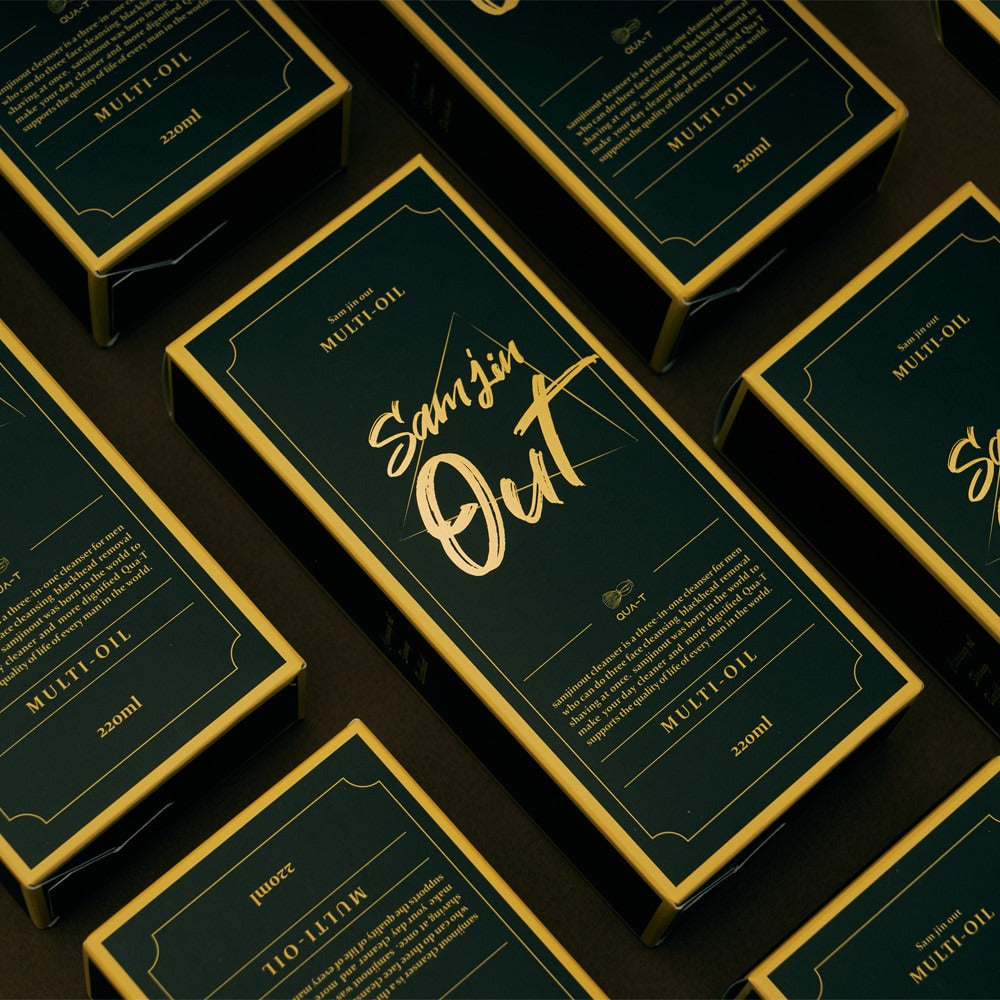 QUA-T Samjin Out Oil 220ml Samjin Out, flacons vert or en série sur fond sombre, étiquette “Multi-Oil”.