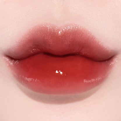 QUA-T The Glass Tattoo Tint, lèvres brillantes sur fond rose, marque QUA-T, rendu “verre” haute brillance.