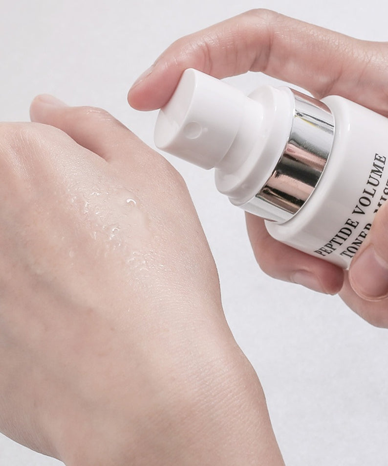 Vaporisateur hydratant R828 Peptide Volume Toner Mist appliqué sur la main pour une peau éclatante et revitalisée.