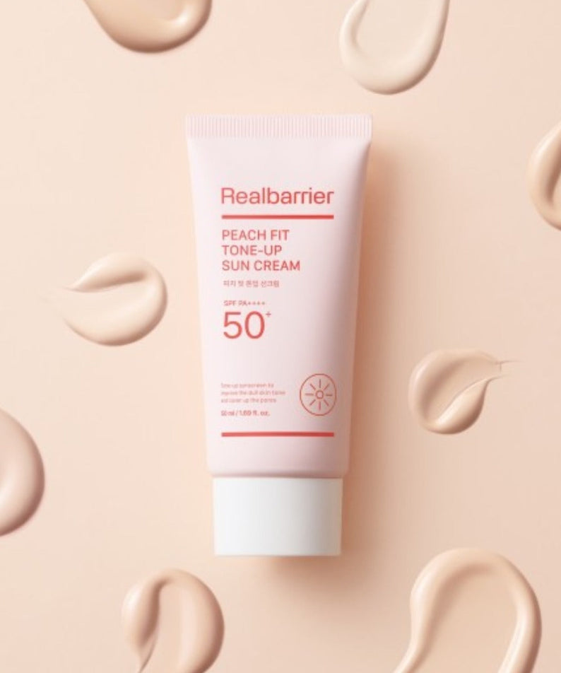 REAL BARRIER Peach Fit Tone-Up Sun Cream 50ml de Realbarrier, crème solaire pêche sur fond beige avec texture de crème.