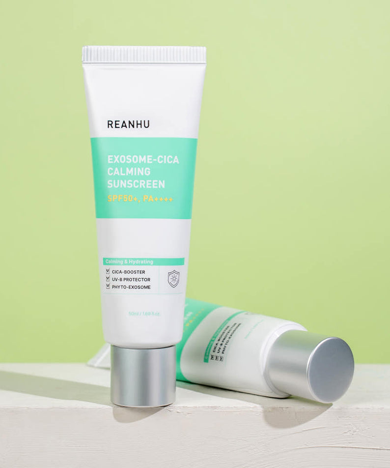 Décris l'image en français: REANHU Exosome Cica Calming Sunscreen 50ml, tube sur fond vert pastel, vue produit.
