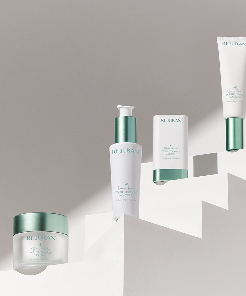 Décris l'image en français : REJURAN Biome Healer Touth Formula Sunscreen 50ml, tubes REJURAN sur fond clair.