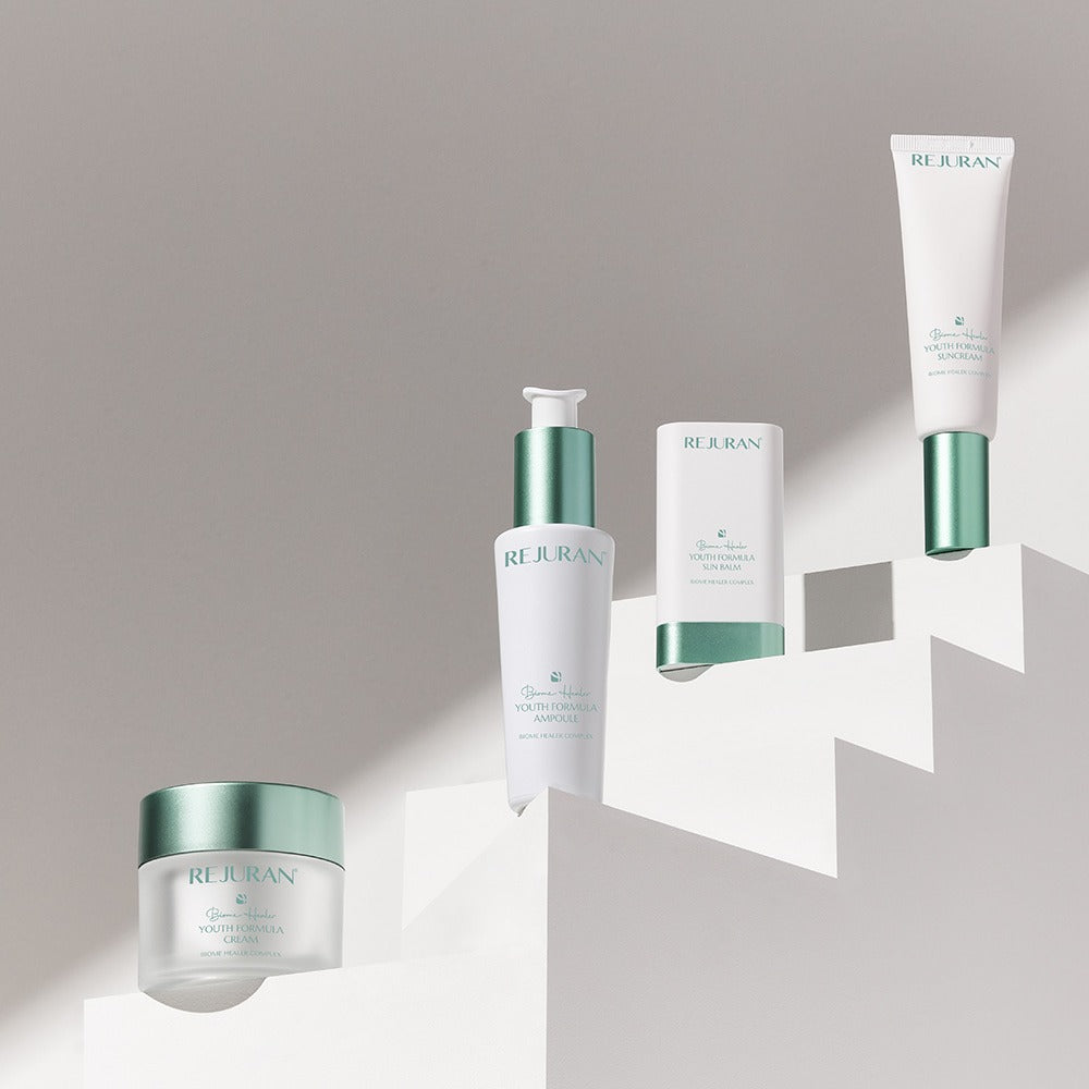 Décris l'image en français : REJURAN Biome Healer Touth Formula Sunscreen 50ml, tubes REJURAN sur fond clair.