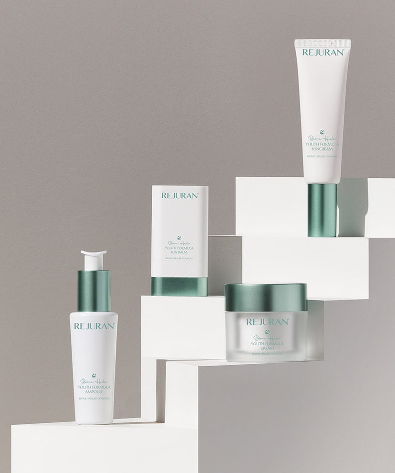 Décris l’image en français : REJURAN Biome Healer Touth Formula Sunscreen 50ml de la marque REJURAN sur présentoir blanc.