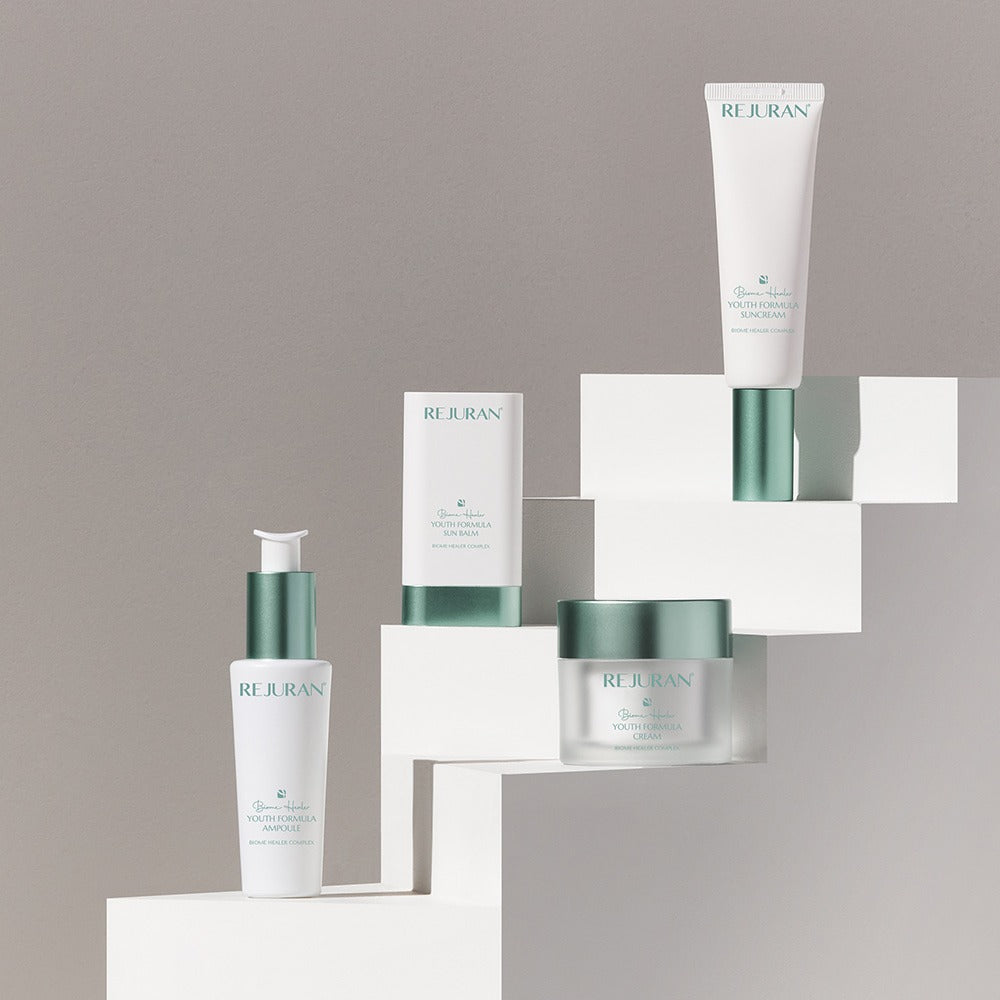 Décris l’image en français : REJURAN Biome Healer Touth Formula Sunscreen 50ml de la marque REJURAN sur présentoir blanc.