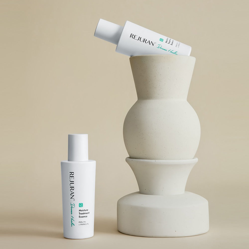 Décris l'image en français : REJURAN Derma Healer Moisture Treatment Essence 70g de la marque REJURAN, flacon sur fond beige.