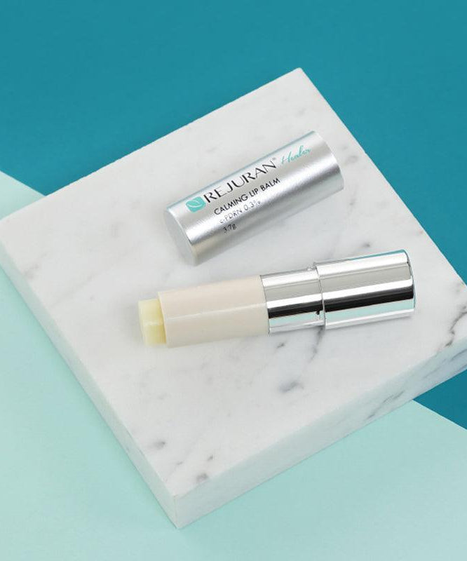Baume à lèvres apaisant sur marbre, REJURAN Healer Calming Lip Balm 3.7g, packaging argenté élégant