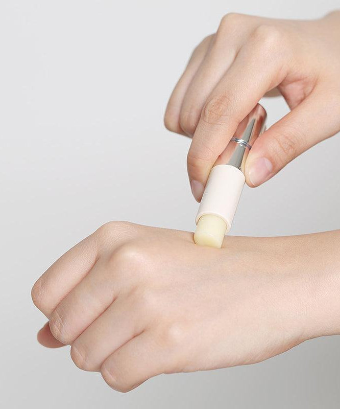 Application du REJURAN Healer Calming Lip Balm 3.7g sur la main, mettant en avant sa texture apaisante et hydratante.