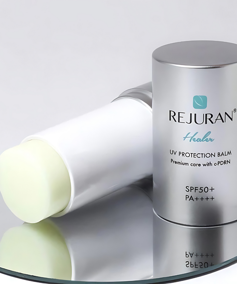 Baume solaire REJURAN Healer UV Protection Balm 19g sur un miroir, offrant une protection SPF50+ pour une peau saine et protégée.
