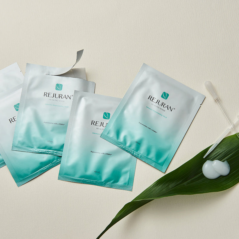 REJURAN Healing Mask de la marque REJURAN, sachets de masque hydratant sur fond beige avec feuille verte