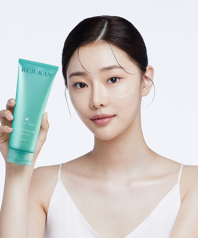 REJURAN Premium Beauty Device : femme tient un tube crème REJURAN, peau éclatante, fond clair, soin beauté.