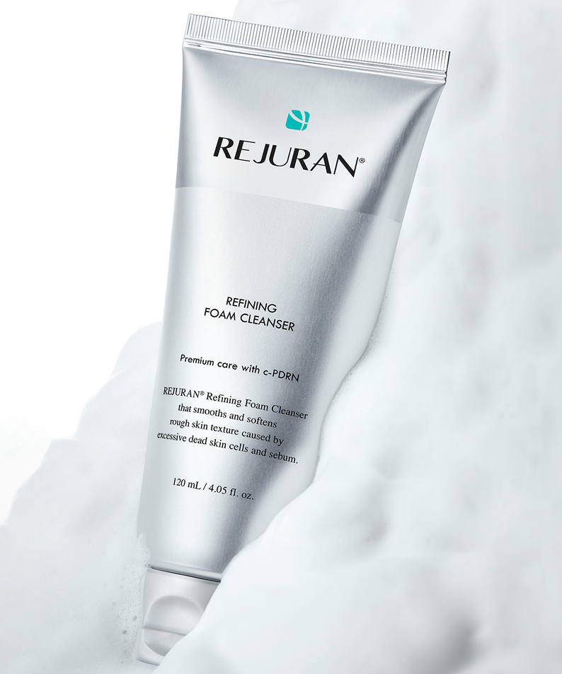 REJURAN  Refining Foam Cleanser 120ml, tube blanc REJURAN sur fond crème et nuage, salle de bain, photo produit.