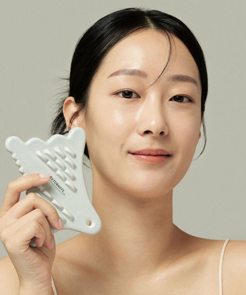 Femme utilisant RETURNITY Guasha sur le visage, outil de massage pour soin de la peau.