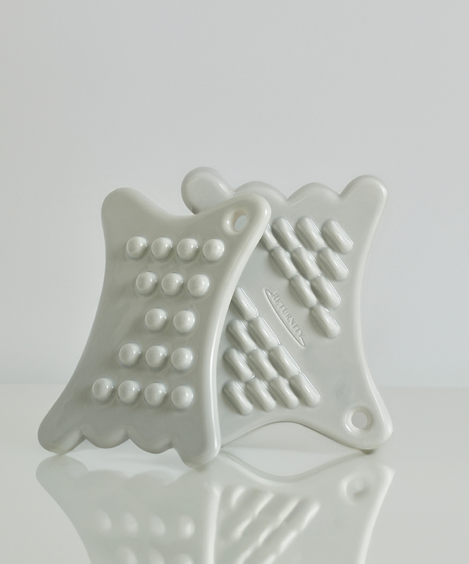 RETURNITY Mini Guasha en céramique blanche sur fond blanc, accessoire de bien-être traditionnel pour massage et soins thérapeutiques.