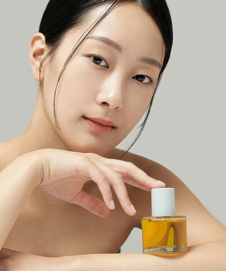 Femme posant avec RETURNITY Organic Jojoba Oil 100% 50ml, soin de beauté naturel.