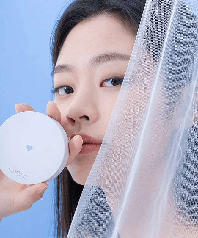 ROMAND Better Than Finish - Femme avec produit cosmétique élégant et moderne, fond bleu apaisant, beauté et sophistication.