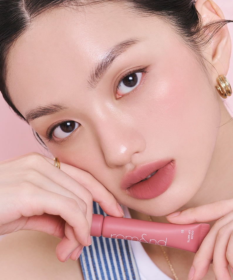 Femme appliquant ROMAND Color Lip Matte, maquillage tendance avec finition mate élégante, parfait pour une allure sophistiquée.