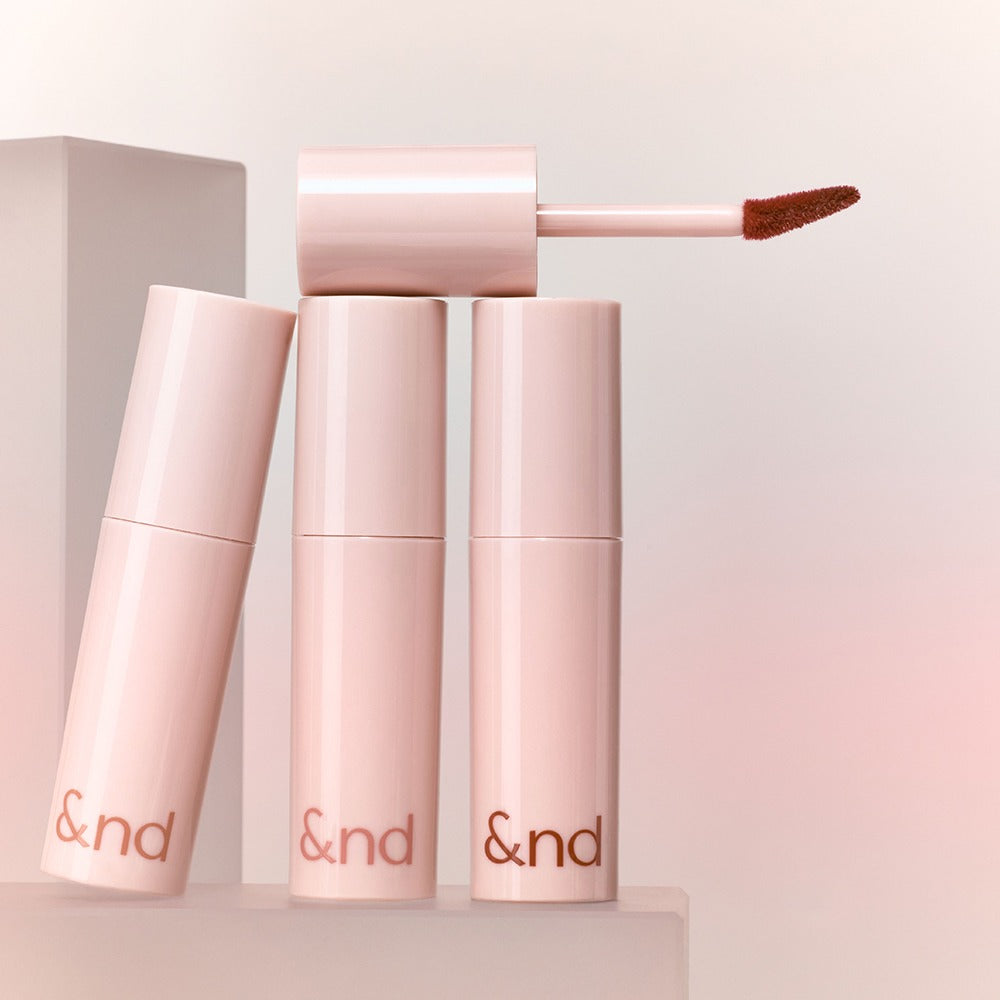 ROMAND  Glassy Bomb Tint de la marque ROMAND, visuel en tube rose et applicateur bourgogne sur fond lumineux