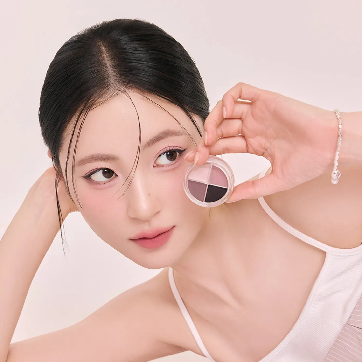 ROMAND  Hanol iPod Liner de la marque ROMAND, appliqué sur le maquillage des yeux, modèle tenant un pot, fond clair.