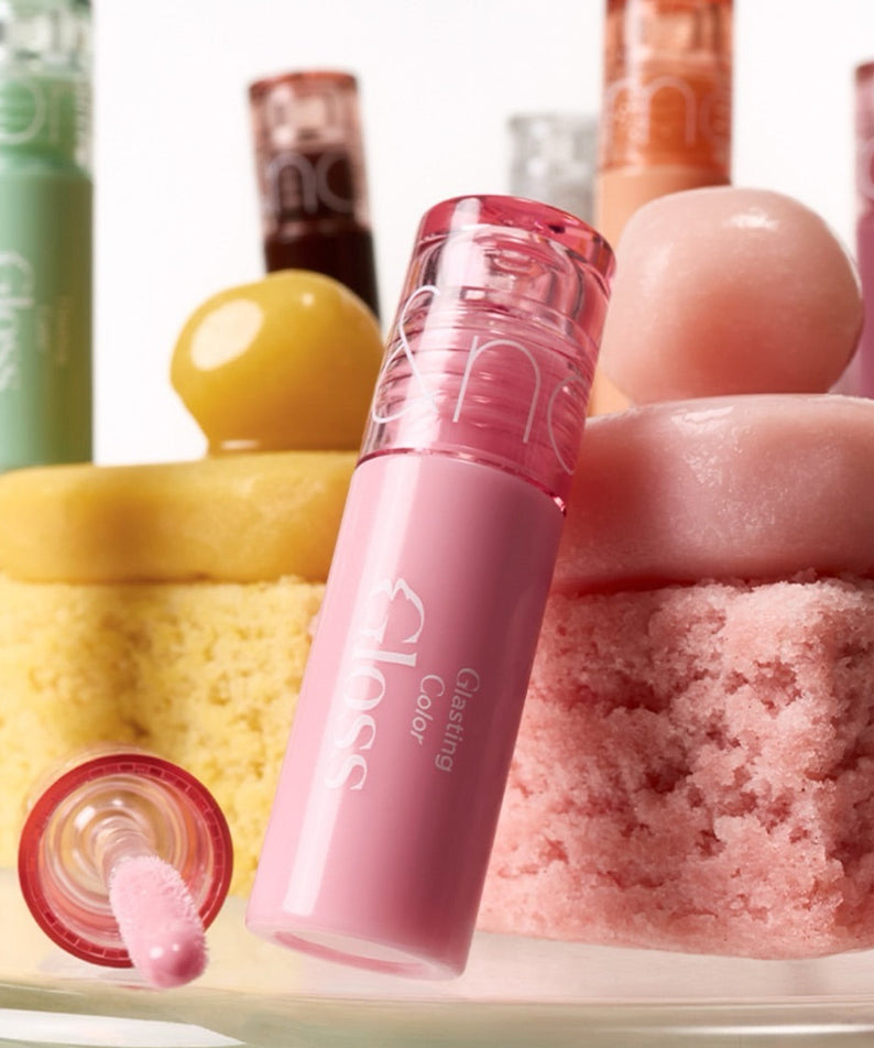 ROMAND MINI Glasting Color Gloss, gloss rose en vitrine avec produits de beauté et flacons colorés en arrière-plan