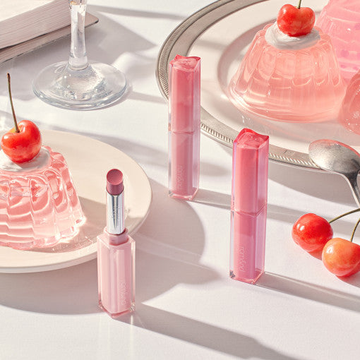 ROMAND Sheer Tinted Stick de ROMAND, sur fond crème avec lumière douce, baumes rose translucides et flacons décoratifs