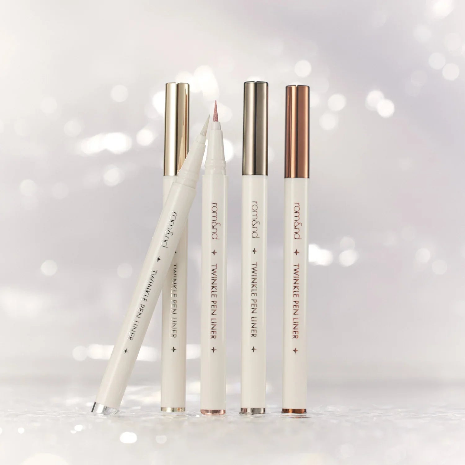 ROMAND Twinkle Pen Liner de la marque ROMAND, stylos eyeliner brillants sur fond blanc scintillant