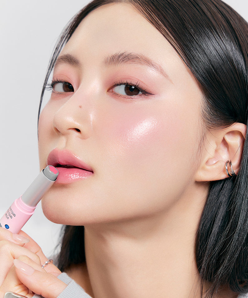 ROMAND x Joanne Friends Glasting Melting Balm, femme appliquant un baume rosé, maquillage glowy, packaging rose sur fond clair.