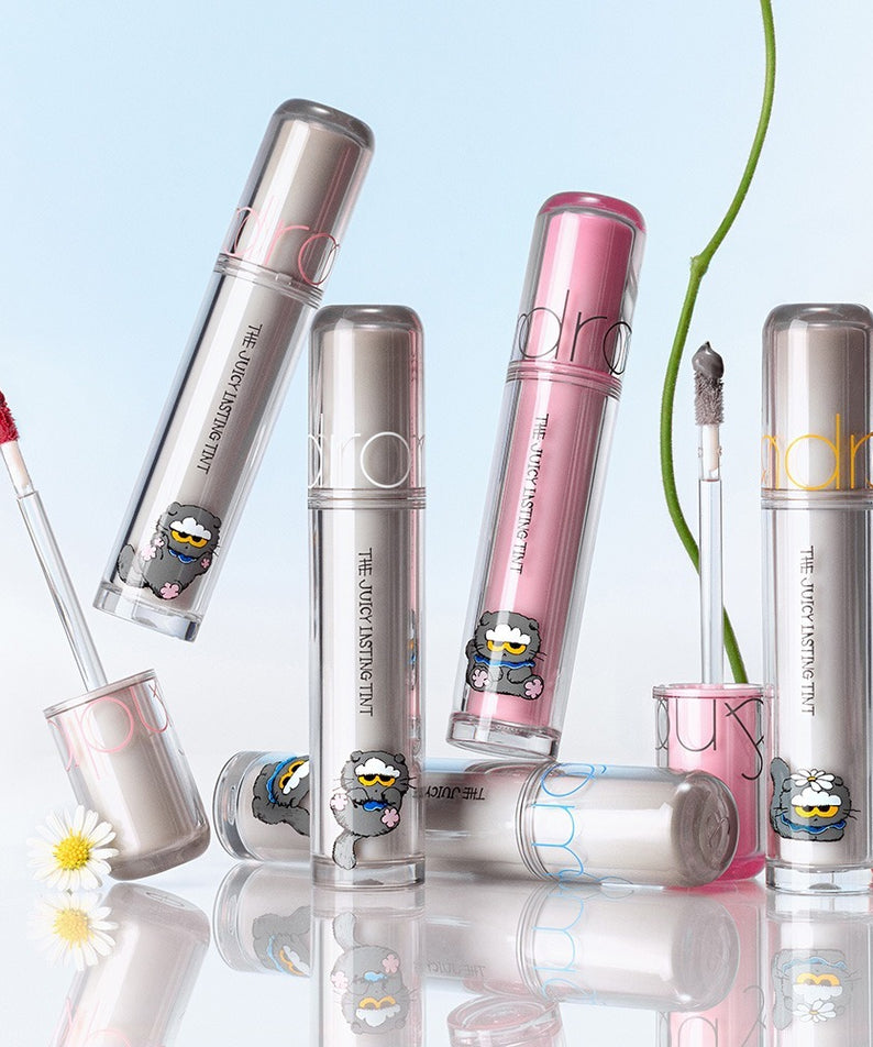 ROMAND x Joanne Friends The Juicy Lasting Tint, tints de lèvres ROMAND en pack, fond bleu et reflets, maquillage.