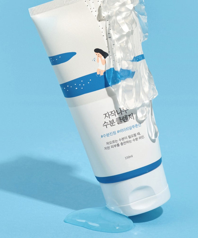 ROUND LAB Birch Juice Moisturizing Cleanser 150ml sur fond bleu avec du nettoyant coulant. Image du produit hydratant en avant-plan.