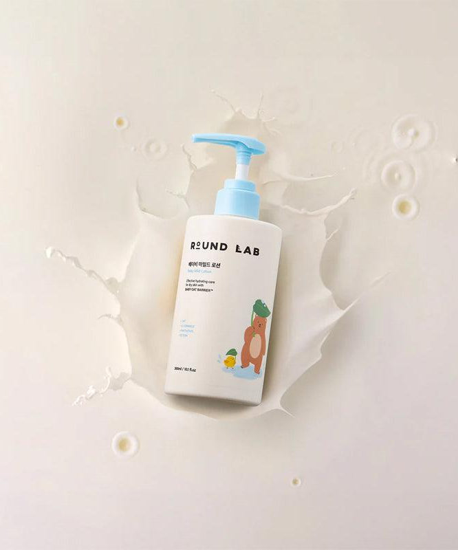 Bouteille de ROUND LAB Baby Mild Lotion 300ml, lotion douce pour bébé avec pompe bleue sur fond beige clair.