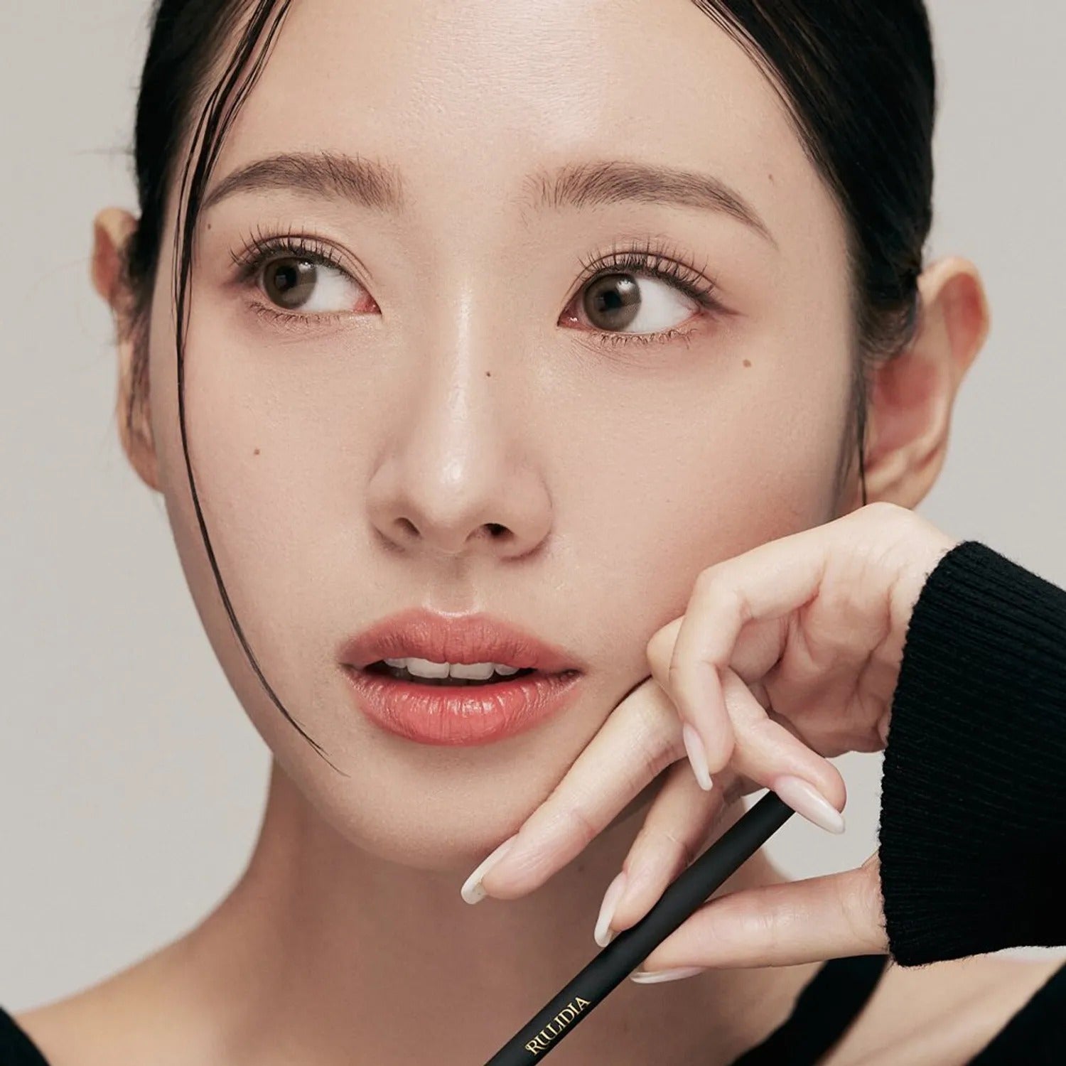 RULIDIA Easy Detail Brow, maquillage sourcils de la marque RULIDIA : main ajuste l’outil sur le visage, fond clair