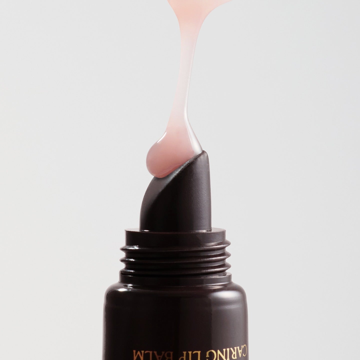 RULIDIA Shining Moment Caring Lip Balm 8g, baume lèvres appliqué en goutte sur flacon noir, fond clair.