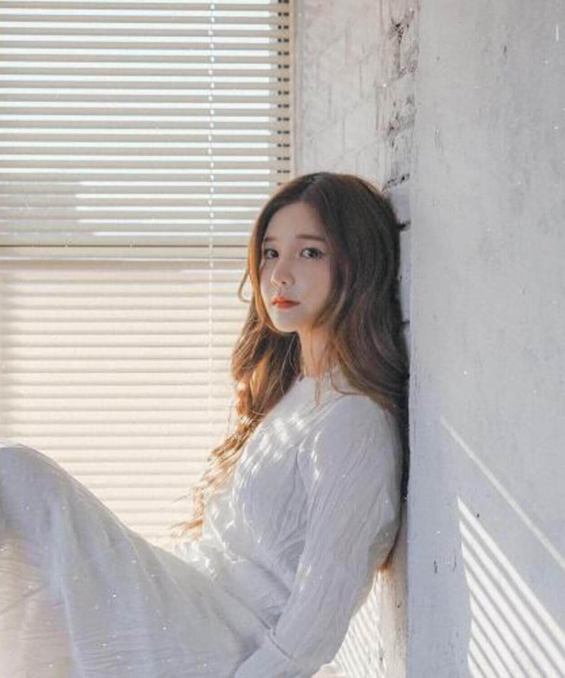 SAEVOM - [13] - Album Kpop par SAEVOM : jeune femme kpop assise près d’une fenêtre, ambiance studio émotionnelle