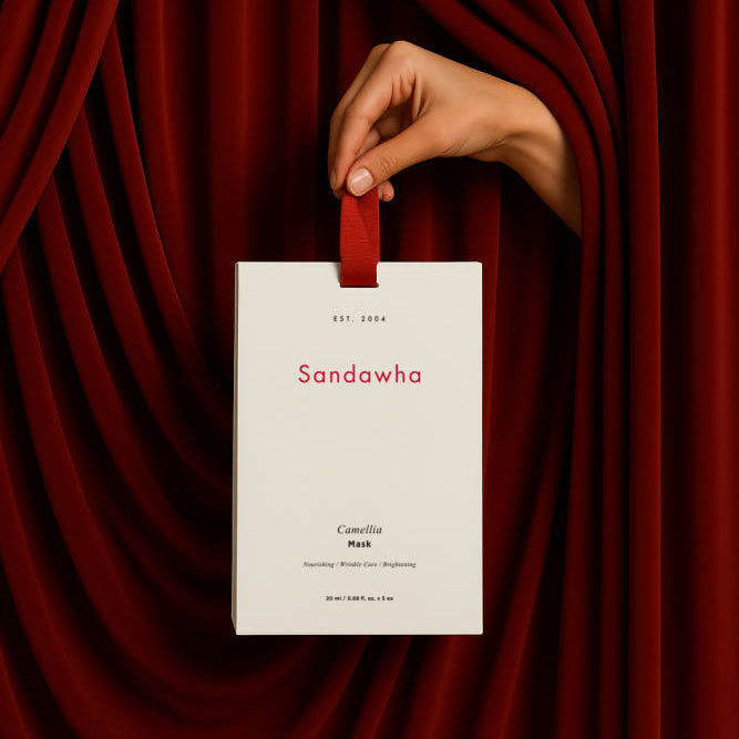 SANDAWHA Camellia Mask 5-piece set, boîte tenue dans une main sur tissu rouge, marque SANDAWHA, présentation élégante.