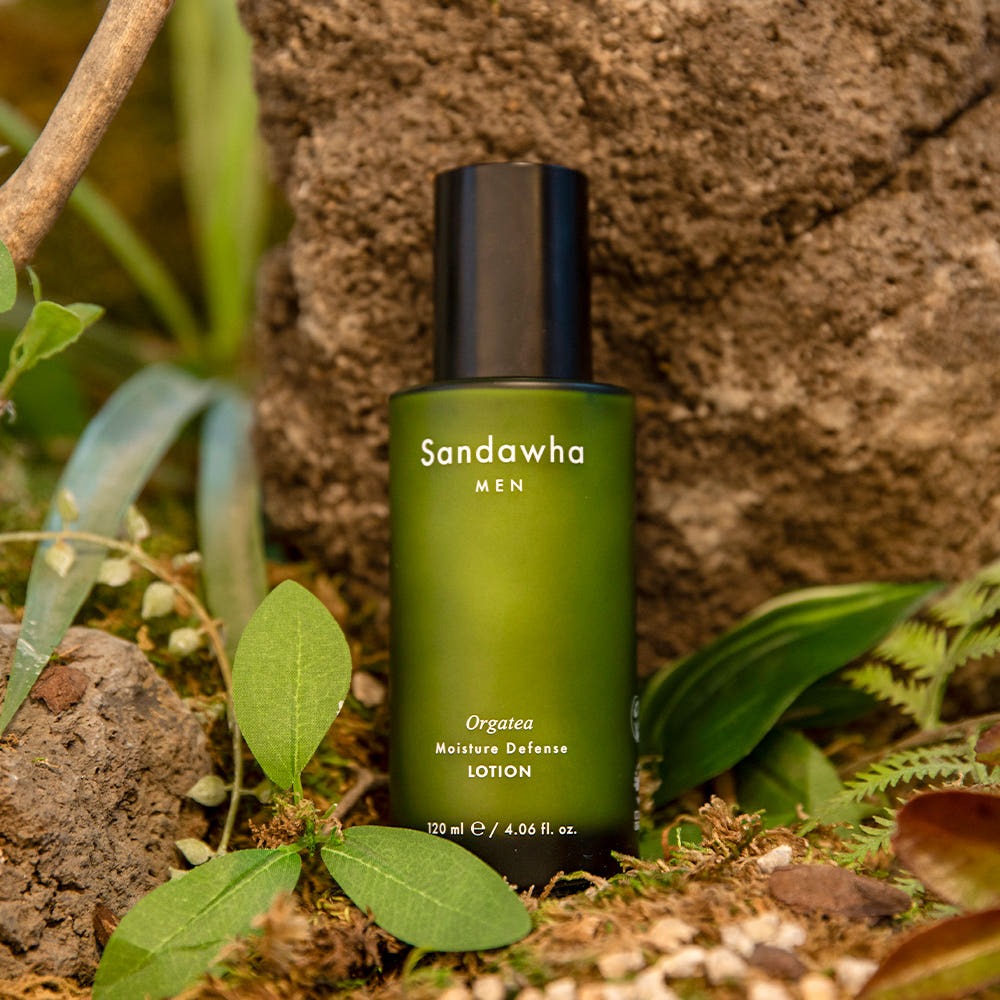 SANDAWHA For Men Orgatea Moiture Defense Lotion 120ml, flacon vert sur rocher naturel avec feuilles.